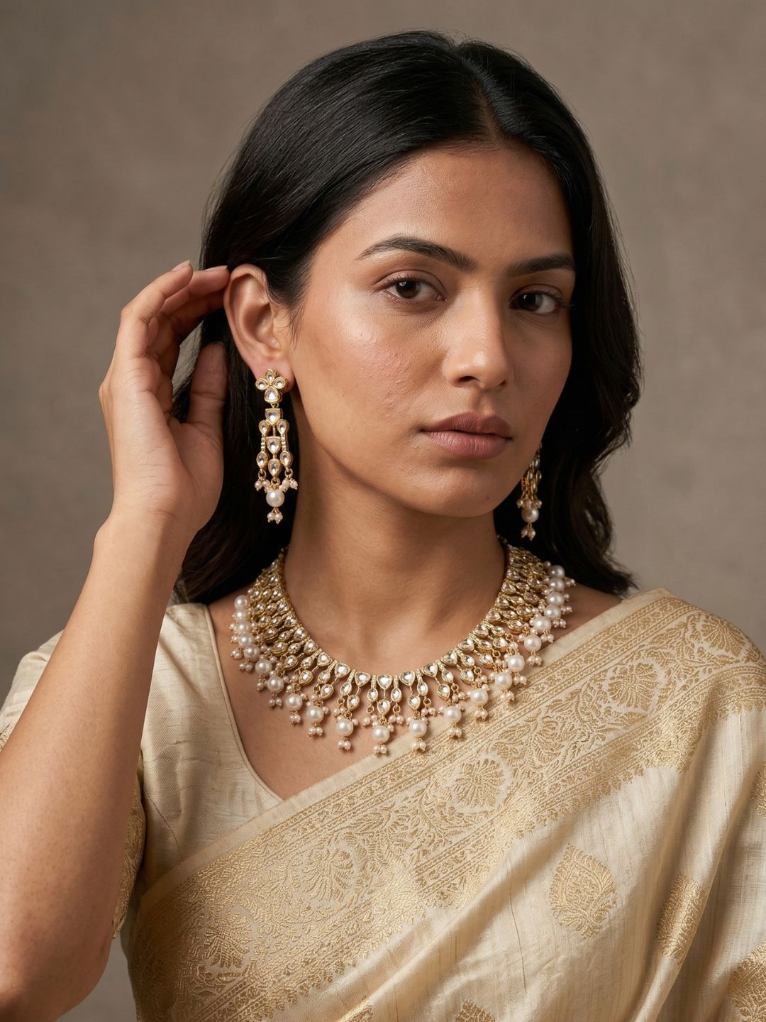 a women wearing a traditional off white saree with gold plated white polki kundan necklace set 