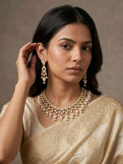 a women wearing a traditional off white saree with gold plated white polki kundan necklace set 