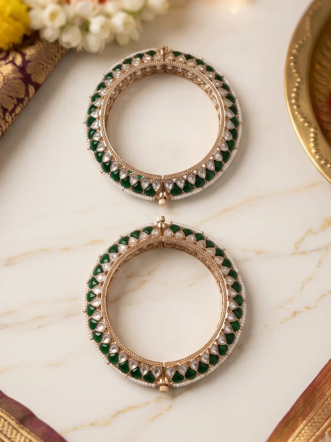 Handcrafted gold-plated Kundan bangles featuring sparkling Kundan stones, elegant pearl borders, and emerald green enamel detailing, perfect for bridal wear, weddings, festive occasions, and traditional Indian jewellery.