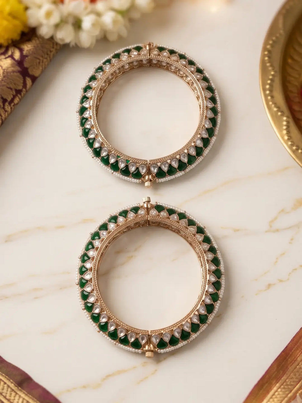 Handcrafted gold-plated Kundan bangles featuring sparkling Kundan stones, elegant pearl borders, and emerald green enamel detailing, perfect for bridal wear, weddings, festive occasions, and traditional Indian jewellery.