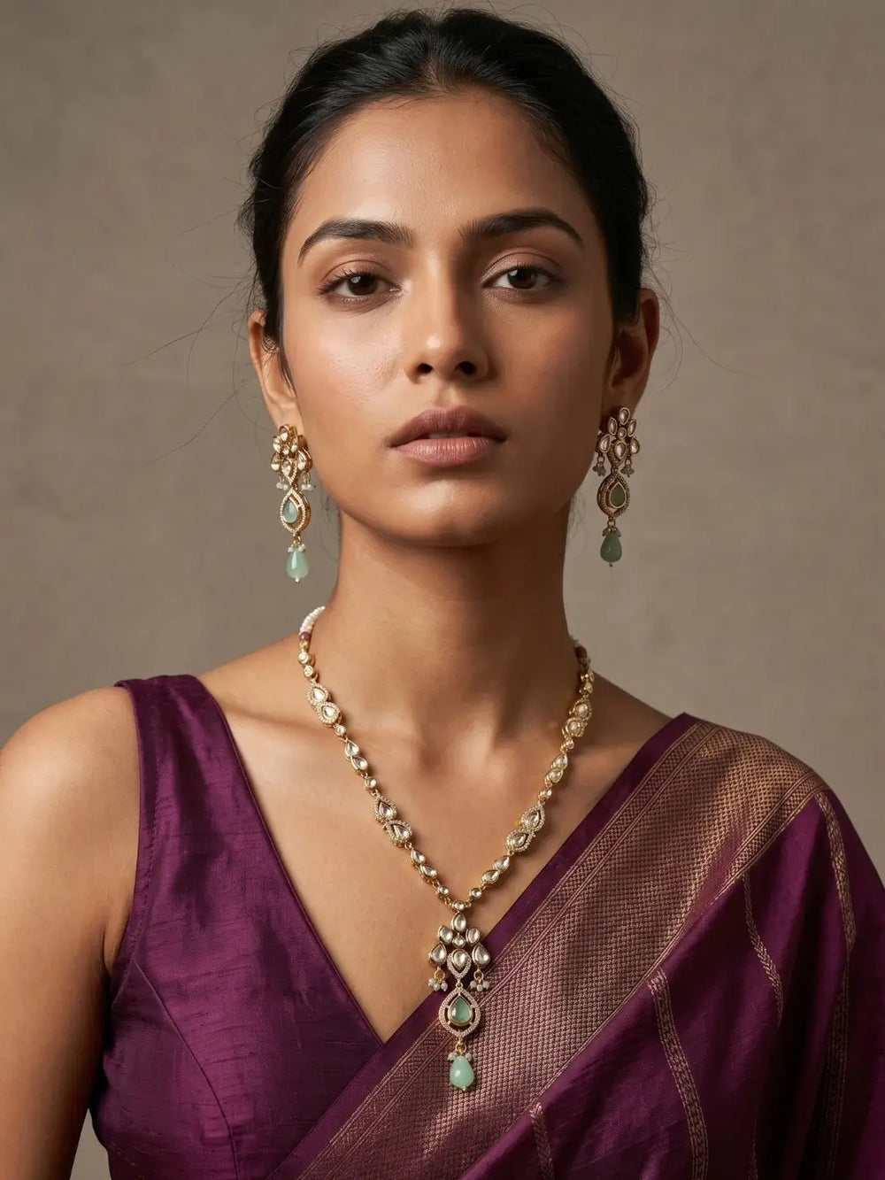 Woman wearing a purple saree with gold-plated polki pendant jewelry set against a neutral background