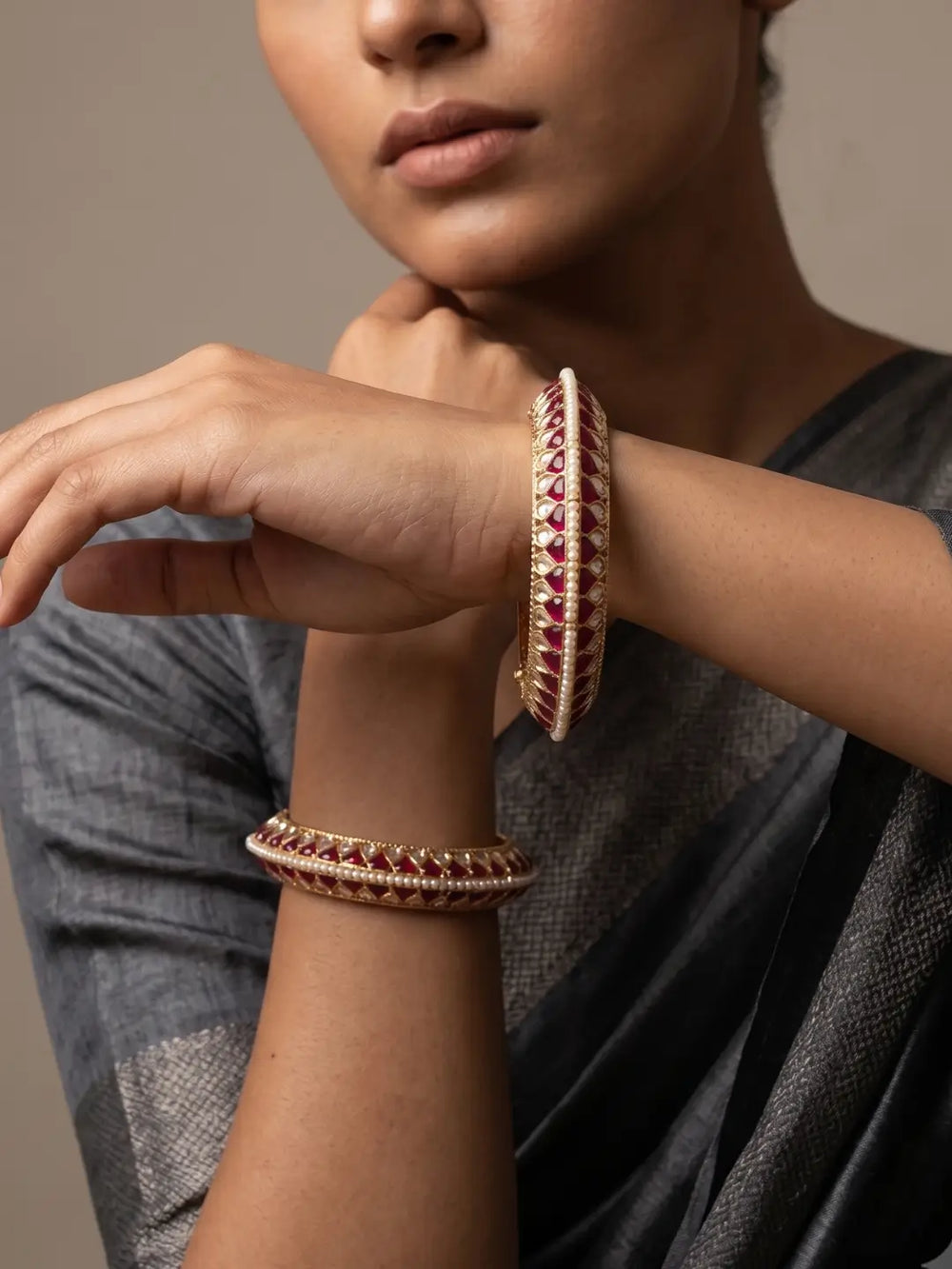 Handcrafted gold-plated Kundan bangles featuring sparkling Kundan stones, elegant pearl borders, and ruby red enamel detailing, perfect for bridal wear, weddings, festive occasions, and traditional Indian jewellery.
