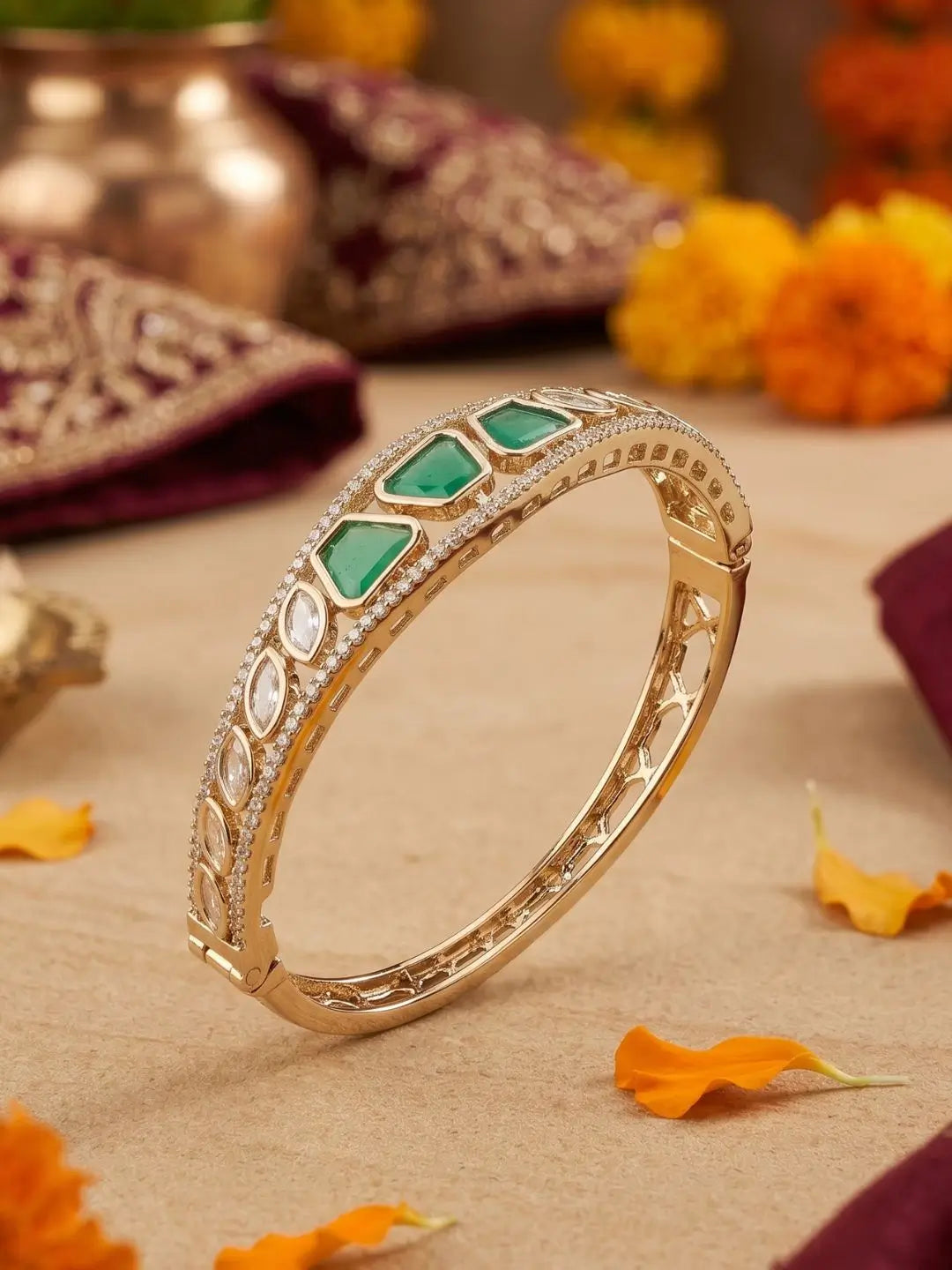 Gold-plated bracelet with green gemstones and kunan  placed on a decorative background