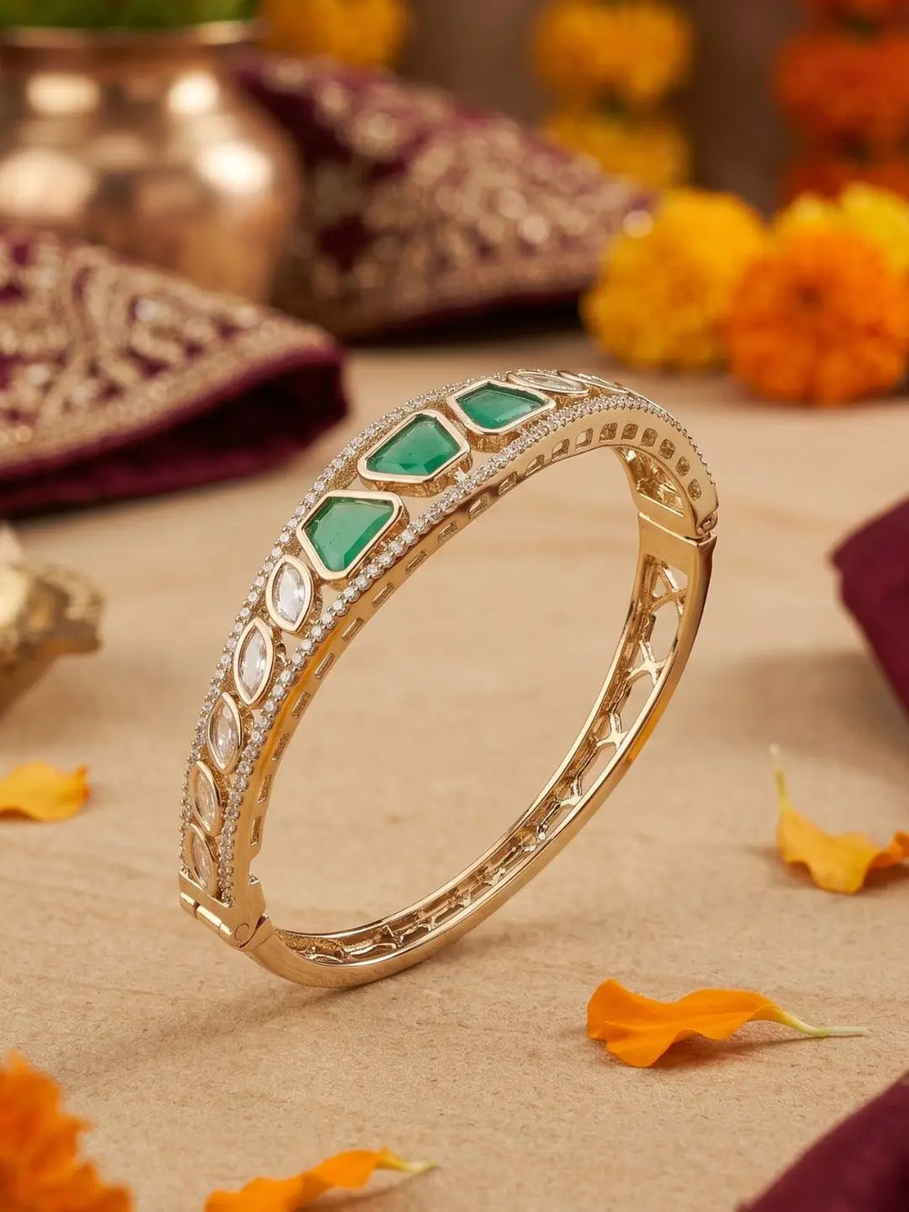 Gold-plated bracelet with green gemstones and kunan  placed on a decorative background