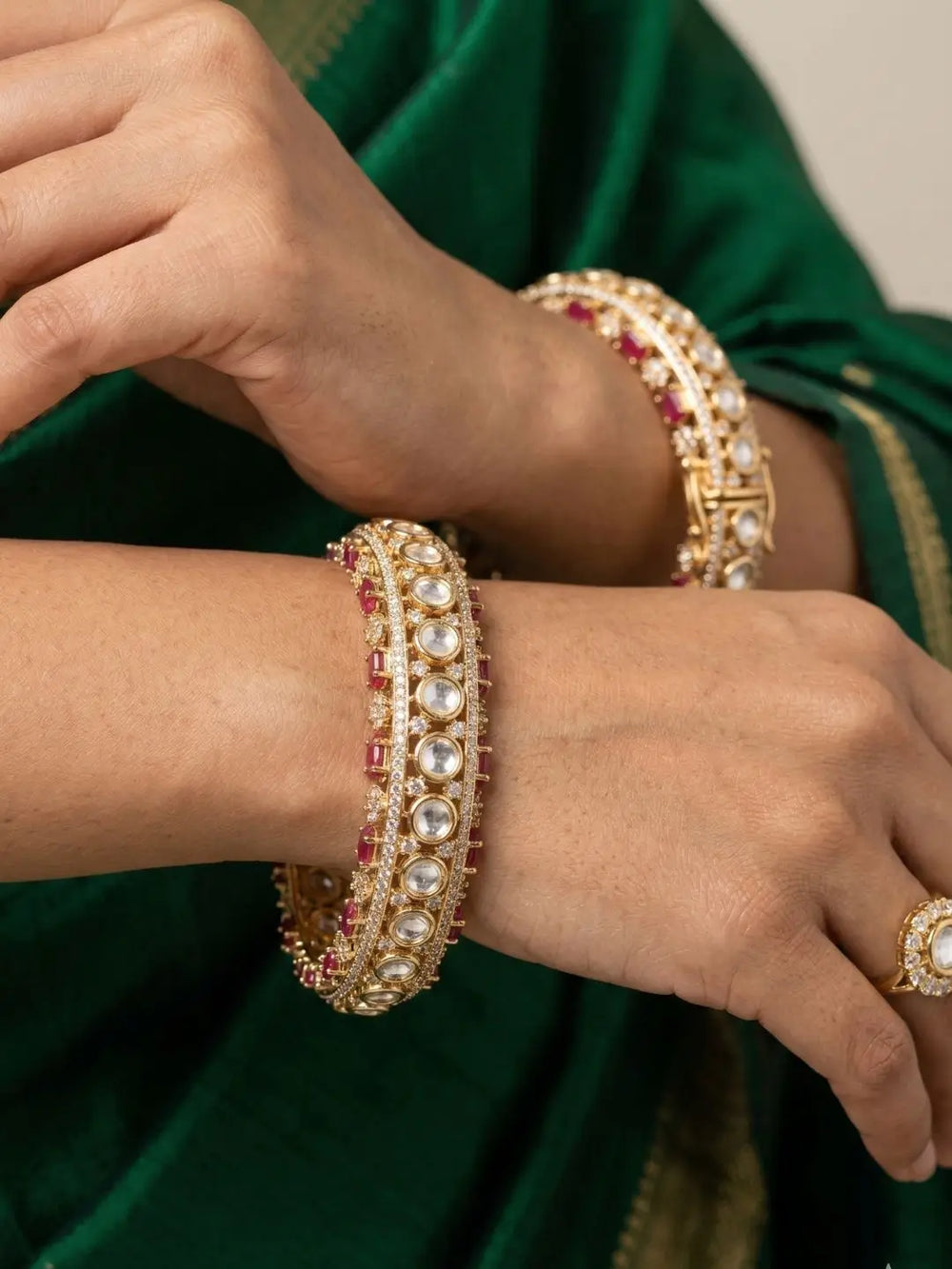 Close-up of hands of a women wearing gold plated studded ruby and kundan bangle on her both wrists
