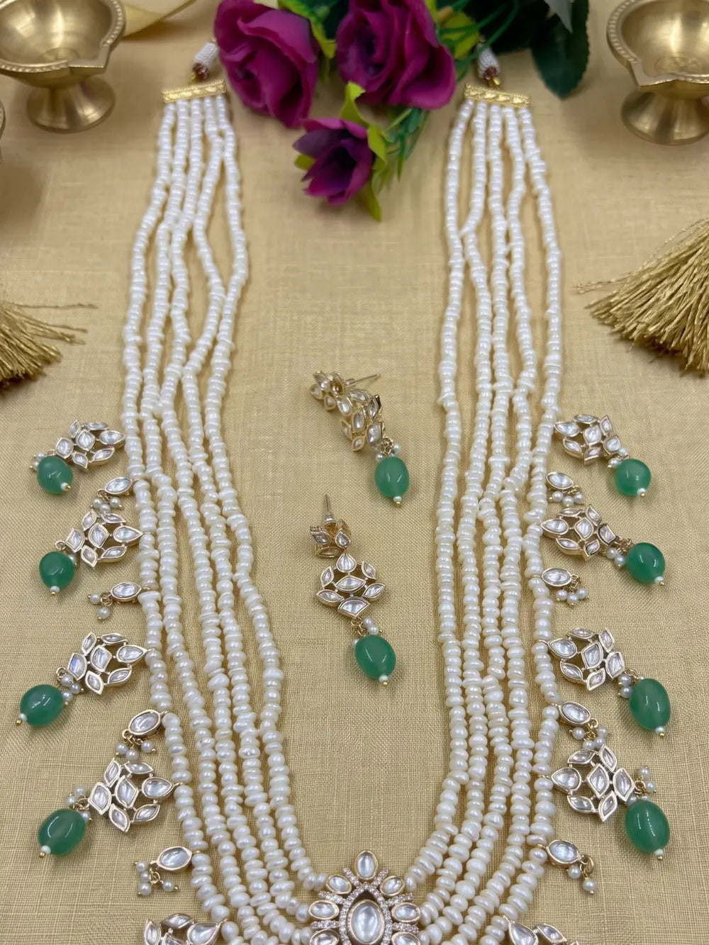  Elegant multi-layer pearl long necklace set featuring a handcrafted Kundan pendant with emerald green bead drops, ruby-inspired centre stone, and matching earrings, perfect for bridal wear, weddings, festive occasions, and traditional Indian jewellery.