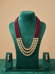 A three-layer re stones beaded kundan necklace set displayed on a green velvet mannequin bust, with matching drop earrings on small stands below. 