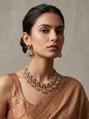 A women is wearing a handcrafted gold-plated floral Kundan necklace set with matching earrings featuring Polki, CZ stones and  multi colour accents, ideal for bridal wear, weddings, festive occasions, and traditional Indian jewellery.