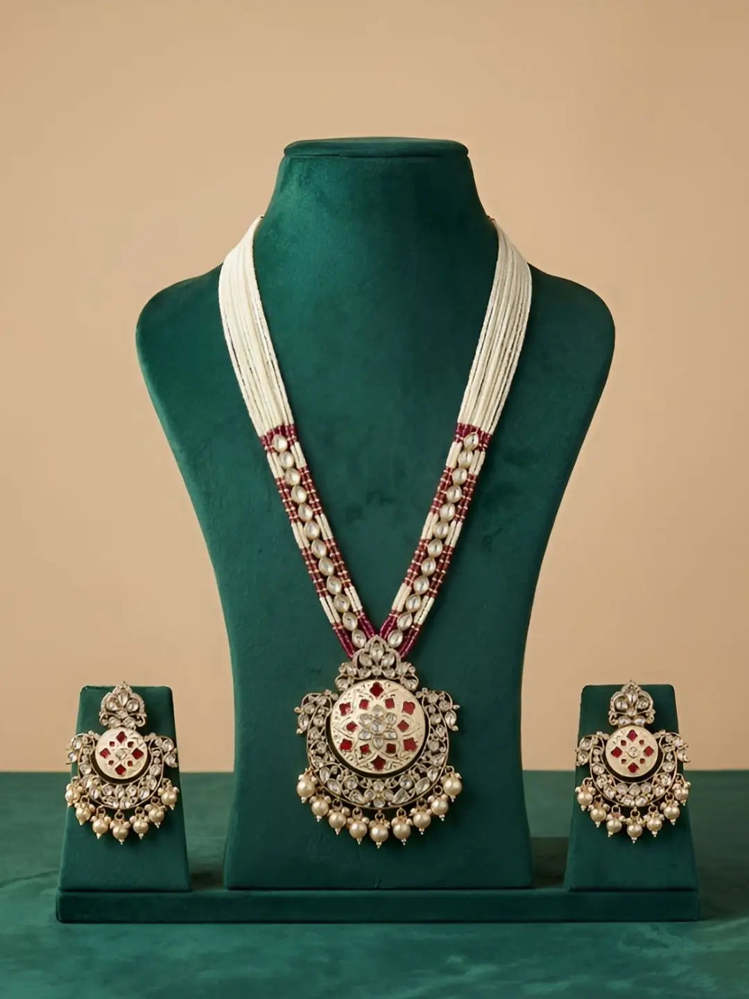 Jewelry set with necklace and earrings on a green mannequin against a beige background