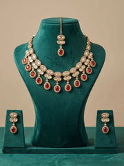 Gold-plated Indian jewelry set featuring a multi-layered necklace, matching pendant, and earrings, embellished with clear crystals and red gemstones, displayed on a teal velvet mannequin bust.