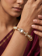 A close-up of a woman's wrist wearing an ornate rose gold-toned bracelet with multiple white polki and cz stones, set against her shoulder and hand.