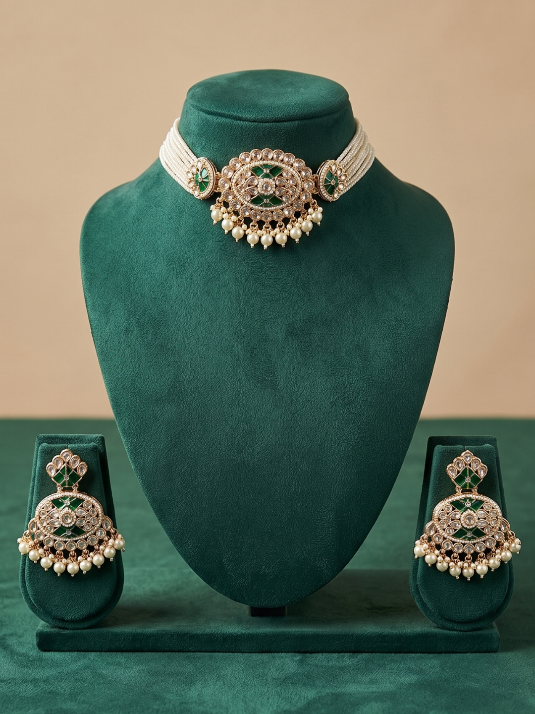 A traditional Indian choker jewelry set featuring a choker necklace and matching earrings, displayed on a dark green velvet stand. The jewelry features a gold-toned filigree base adorned with green stones and white pearl-like beads.