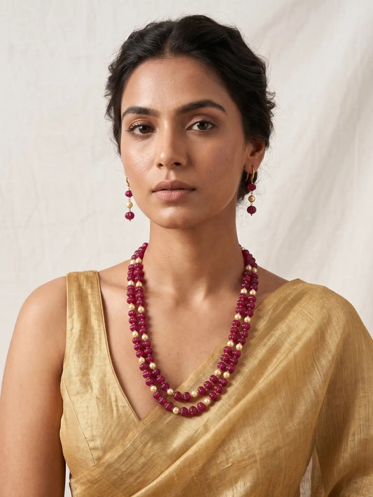 A women wearing a golden saree and a Natural Watermelon Shaped Ruby Red Jade Beaded Necklace With Drop Earrings.